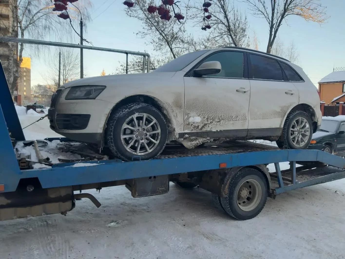 Серебристый легковой автомобиль на эвакуаторе зимой