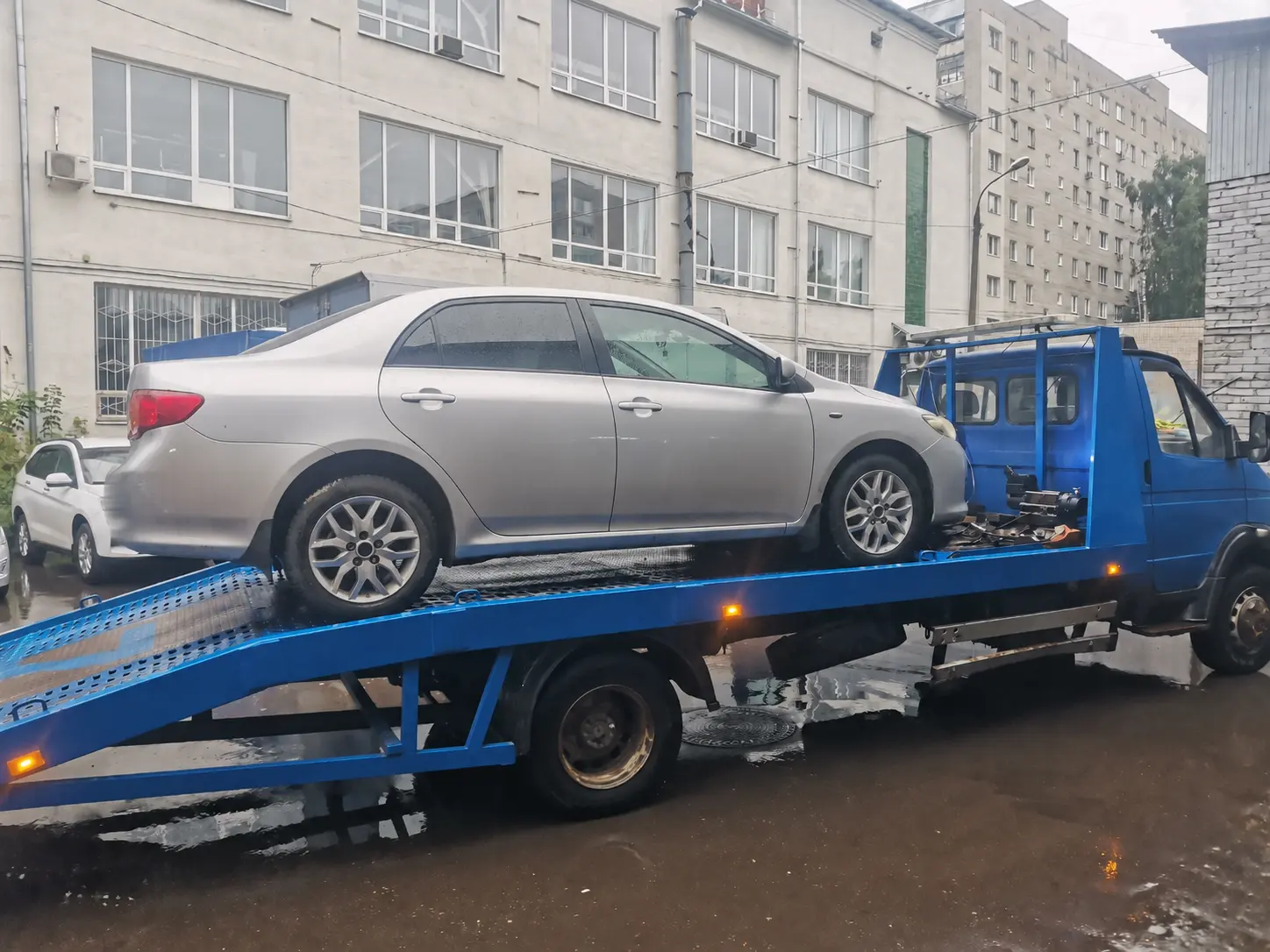 Серебристая Toyota Corolla на синем эвакуаторе